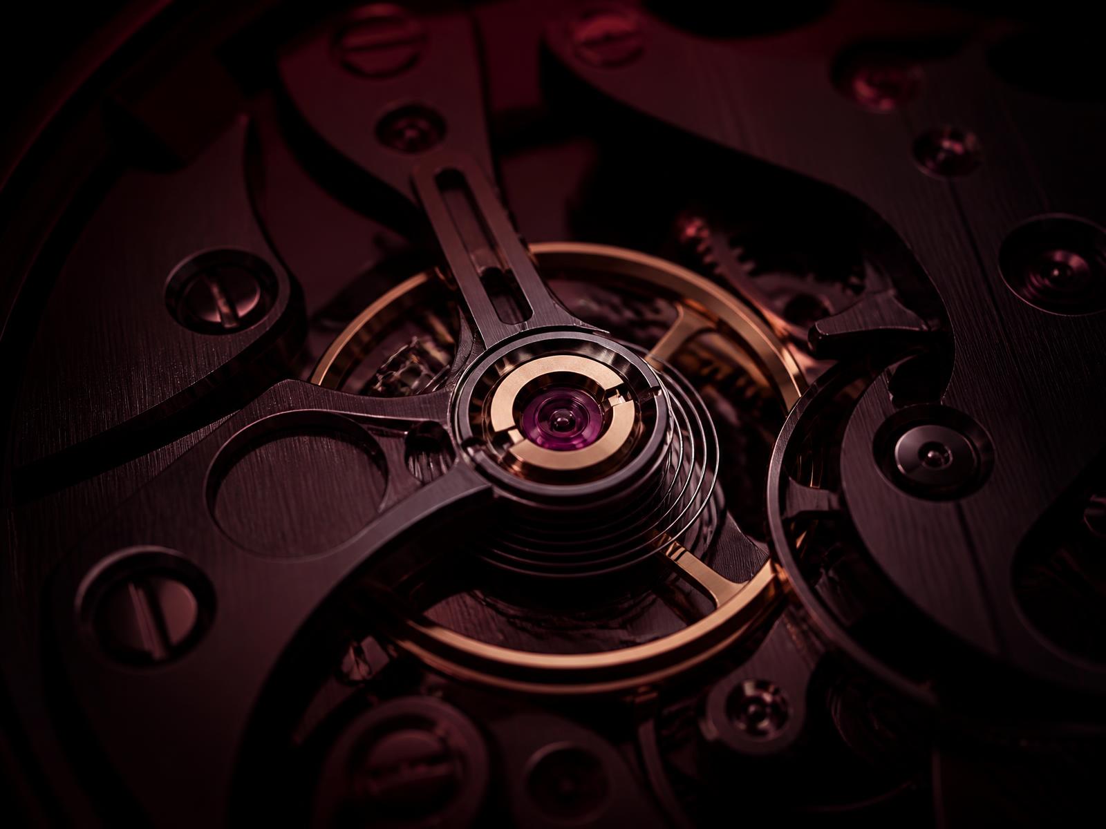 Close detail of a mechanical balance wheel and bridges lit in deep burgundy light